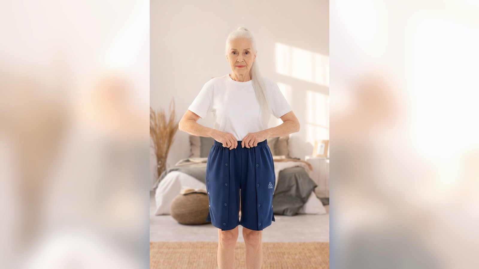 Frau im Schlafzimmer in Pflegeshorts mit Druckknöpfen in Navy, die Leisten lassen sich im Liegen öffnen