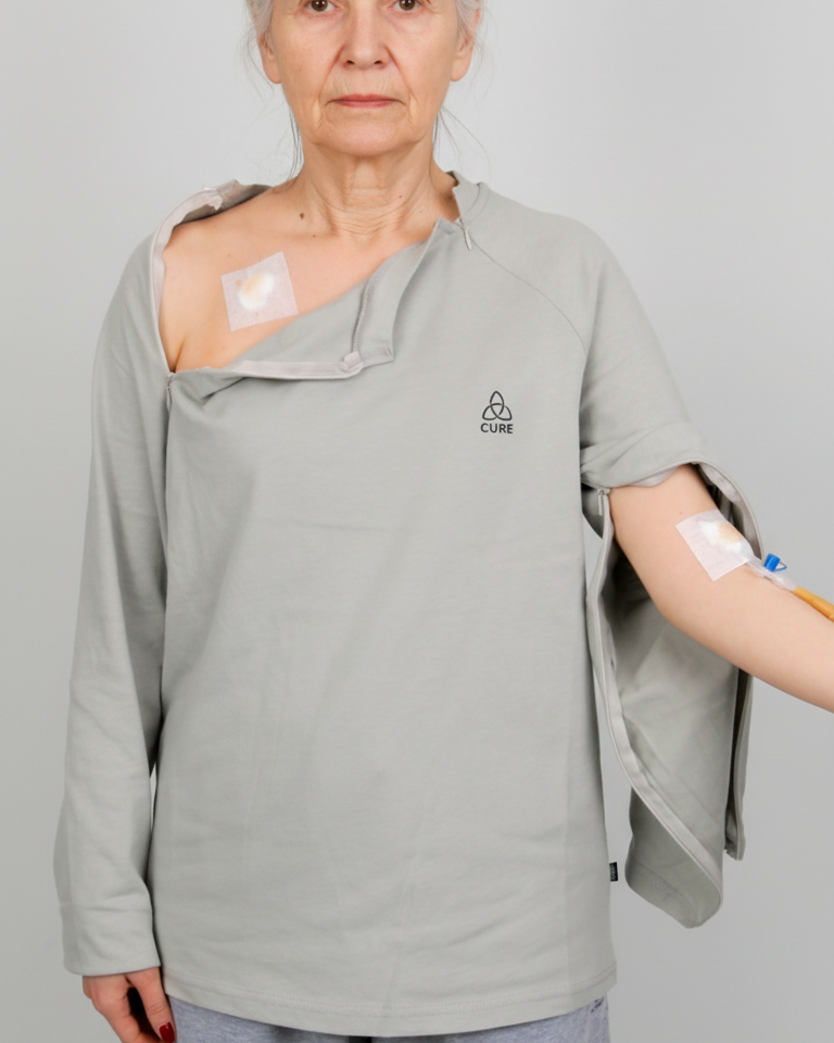 ComfortCure Adaptives Pflegeoberteil mit Port- und Dialysezugang, Grau meliert, Vorderansicht, Brust- und Ärmelreißverschluss geöffnet, Port- und Infusionszugang sichtbar