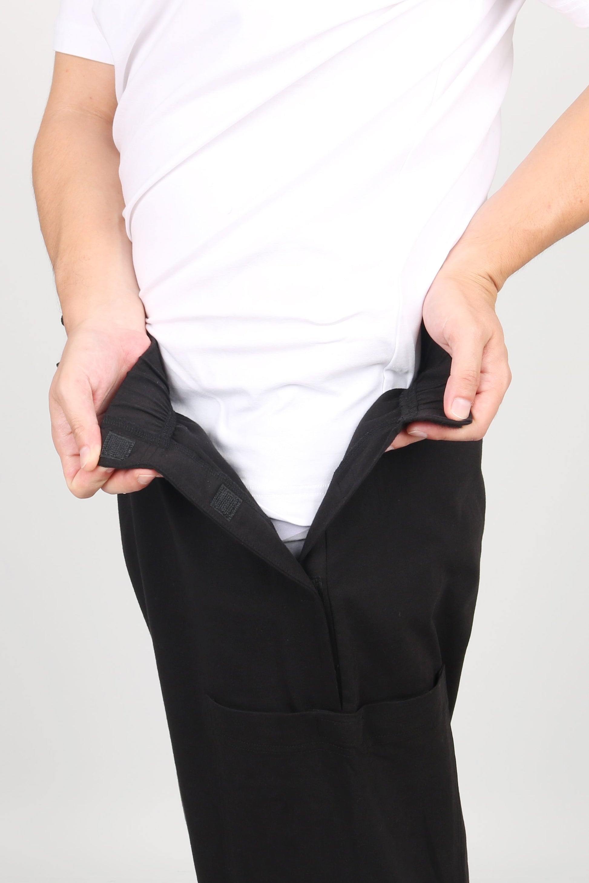 ComfortCure Adaptive Pflegehose für Prostatapatienten (mit Beintaschen), Schwarz, Vorderansicht, Hände öffnen den Klettverschluss am Bund