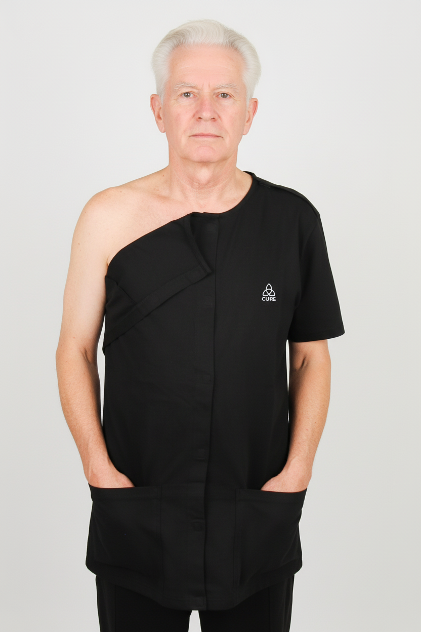 ComfortCure Adaptives Pflegeoberteil für die Zeit nach der Operation, Schwarz, Vorderansicht, rechte Schulter geöffnet, Hände in den Taschen