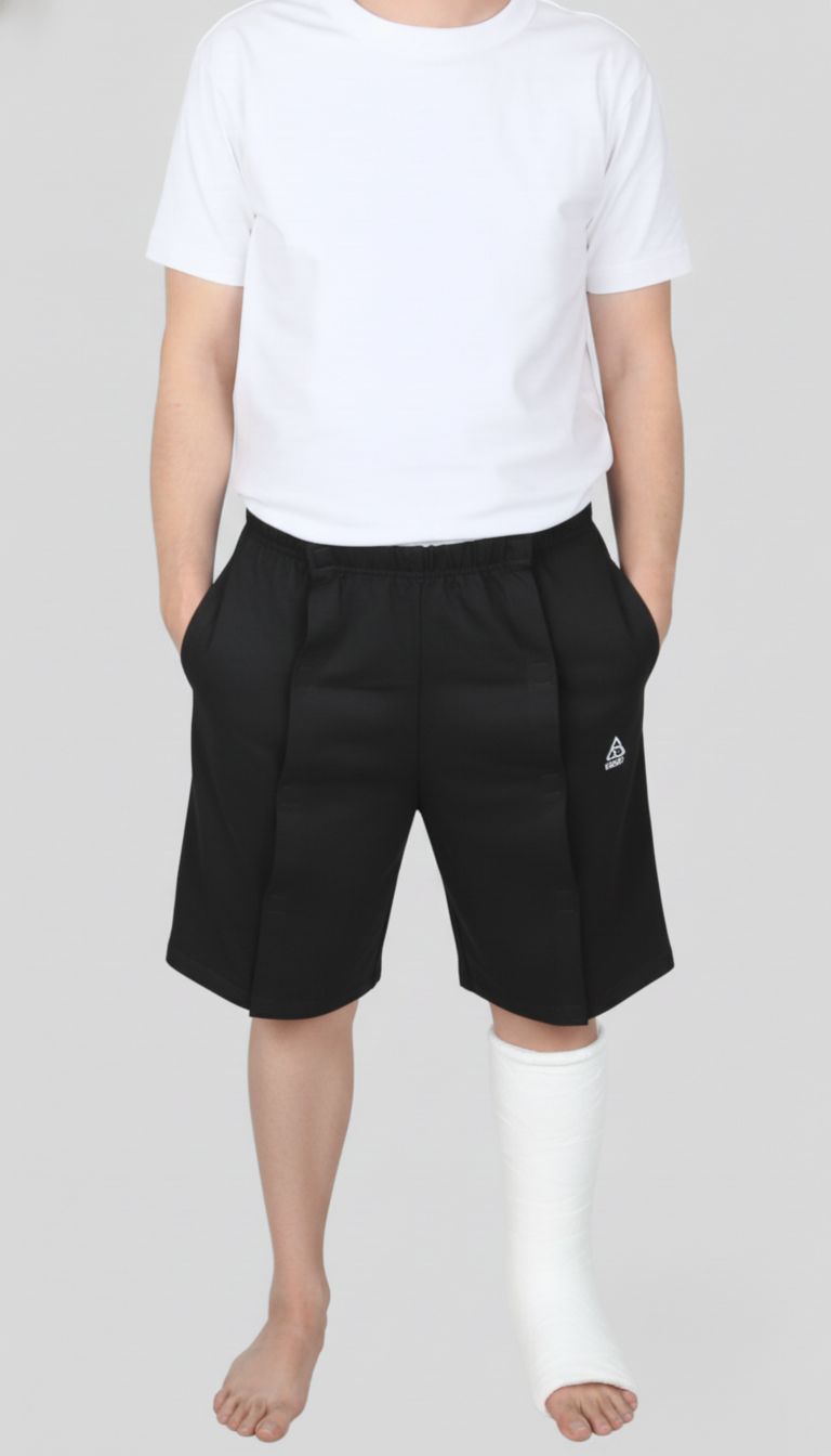 ComfortCure Adaptive Pflegeshorts für bettlägerige Patienten - Klettverschluss, vorne komplett zu öffnen, Schwarz, Vorderansicht geschlossen mit Gips am Unterschenkel