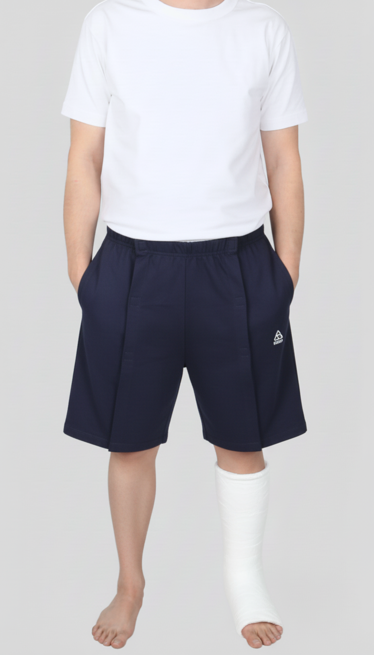 ComfortCure Adaptive Pflegeshorts für bettlägerige Patienten - Klettverschluss, vorne komplett zu öffnen, Navy, Vorderansicht geschlossen, Hände in den Taschen, Gips am Bein