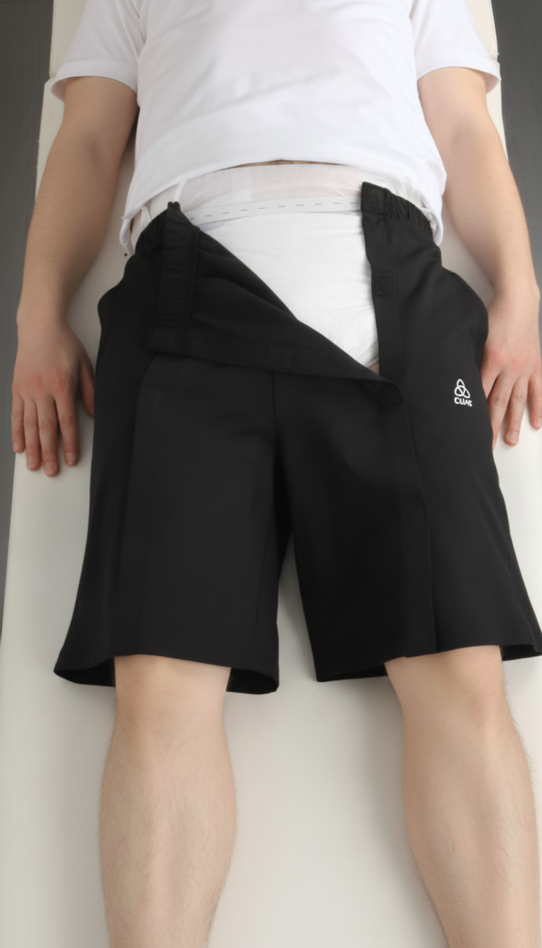 ComfortCure Adaptive Pflegeshorts für bettlägerige Patienten - Klettverschluss, vorne komplett zu öffnen, Schwarz, Aufsicht liegend, Frontklappe geöffnet, Vorlage sichtbar