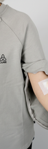ComfortCure Adaptives Pflegeoberteil mit Port- und Dialysezugang, Grau meliert, Detailansicht, Ärmelreißverschluss geöffnet mit Infusionszugang