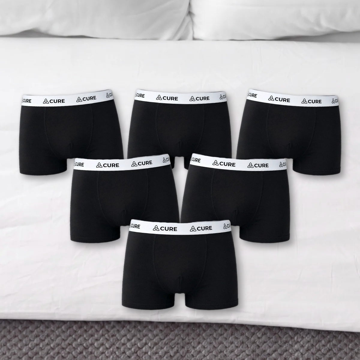 Sechs schwarze ComfortCure Boxershorts auf einem Bett