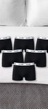 Sechs schwarze ComfortCure Boxershorts auf einem Bett