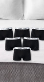 Sechs schwarze ComfortCure Boxershorts auf einem Bett
