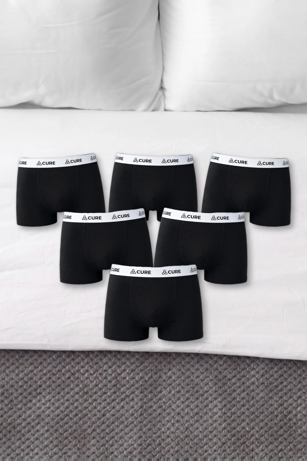 Sechs schwarze ComfortCure Boxershorts auf einem Bett