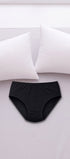 ComfortCure Adaptiver auslaufsicherer Damenslip, Schwarz, auf einem hellen Bett liegend