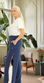 ComfortCure Adaptive Orthopädie-Pflegehose mit Druckknöpfen, Navy, Seitenansicht im Altbau-Wohnzimmer, seitlich geöffnet über einem bandagierten Bein
