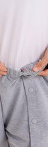 ComfortCure Adaptive Pflegeshorts für bettlägerige Patienten - mit Druckknöpfen, Grau meliert, Detailansicht, Druckknopfleiste am Bund wird geöffnet