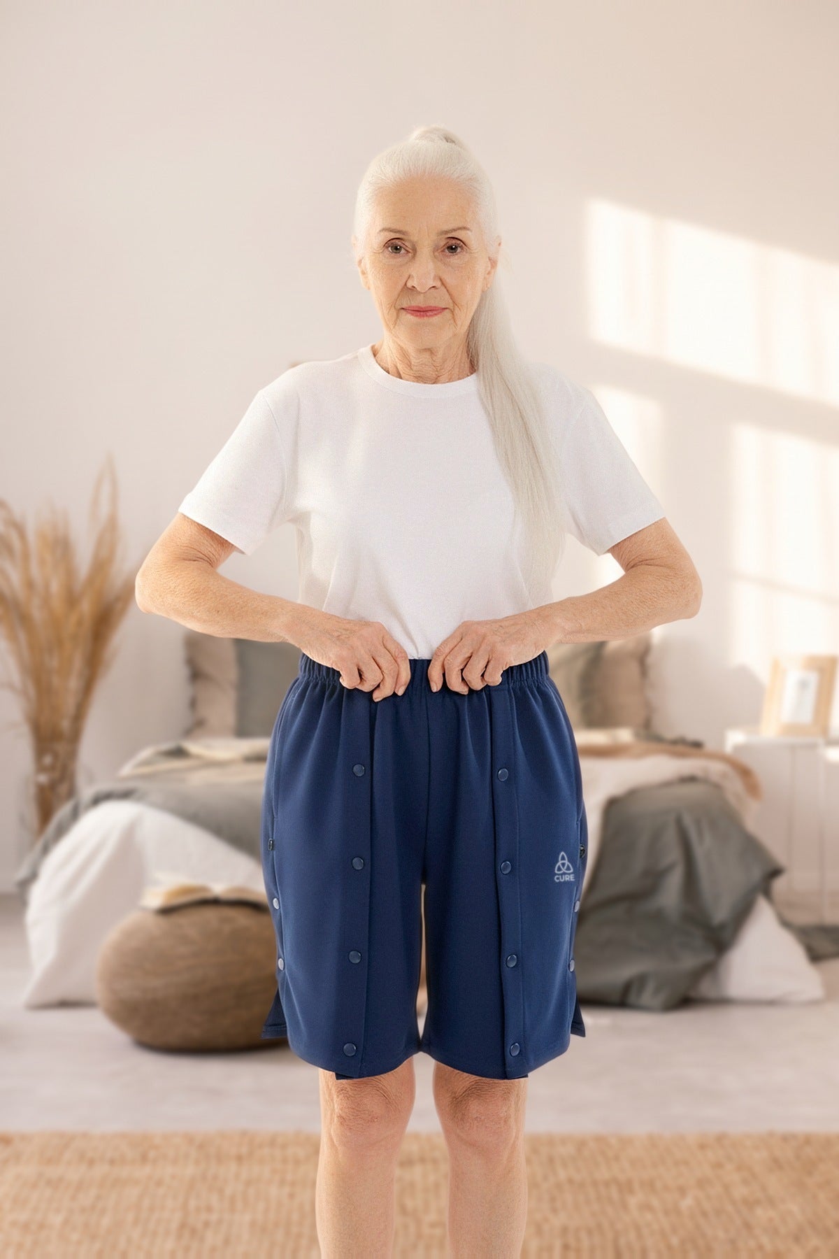ComfortCure Adaptive Pflegeshorts für bettlägerige Patienten mit Druckknöpfen, Navy, Vorderansicht im Schlafzimmer