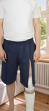 ComfortCure Adaptive Pflegeshorts für bettlägerige Patienten mit Klettverschluss, Navy, Vorderansicht im Wohnzimmer, seitlich geöffnet über einem Gipsbein