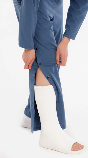 Adaptive Pflegehose, Denimblau, Detailansicht mit offenen Seitendruckknöpfen über weißem Beingips