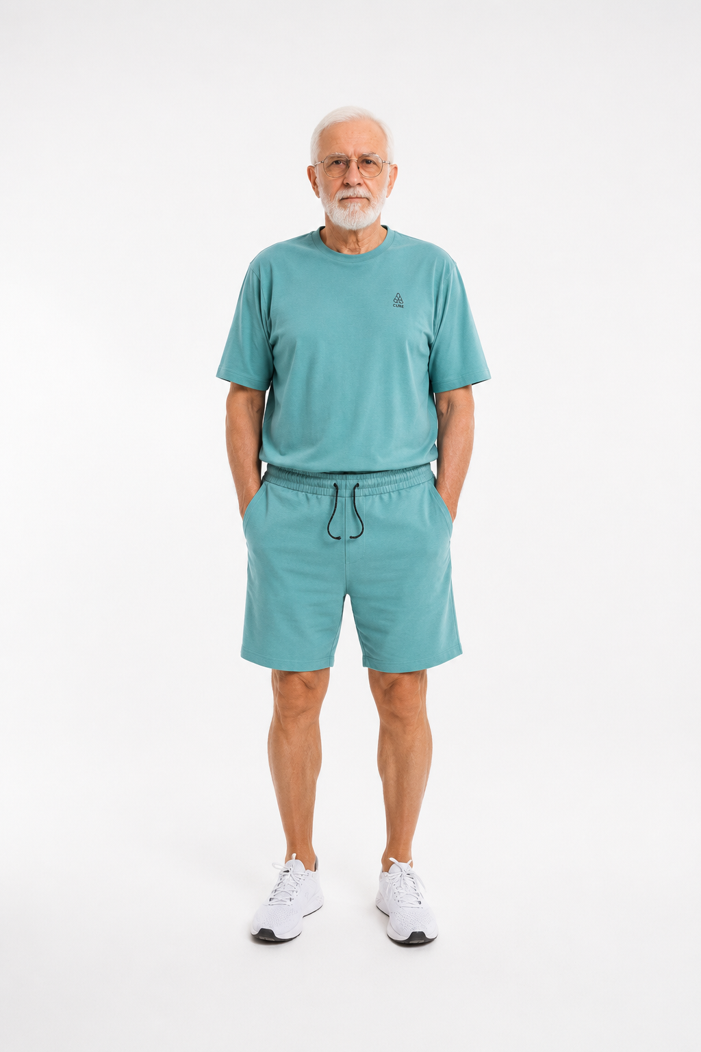 ComfortCure Adaptiver Kurzarm-Pflegeoverall für die Alzheimer- und Demenzpflege, Grün, Vorderansicht, Hände in den Taschen