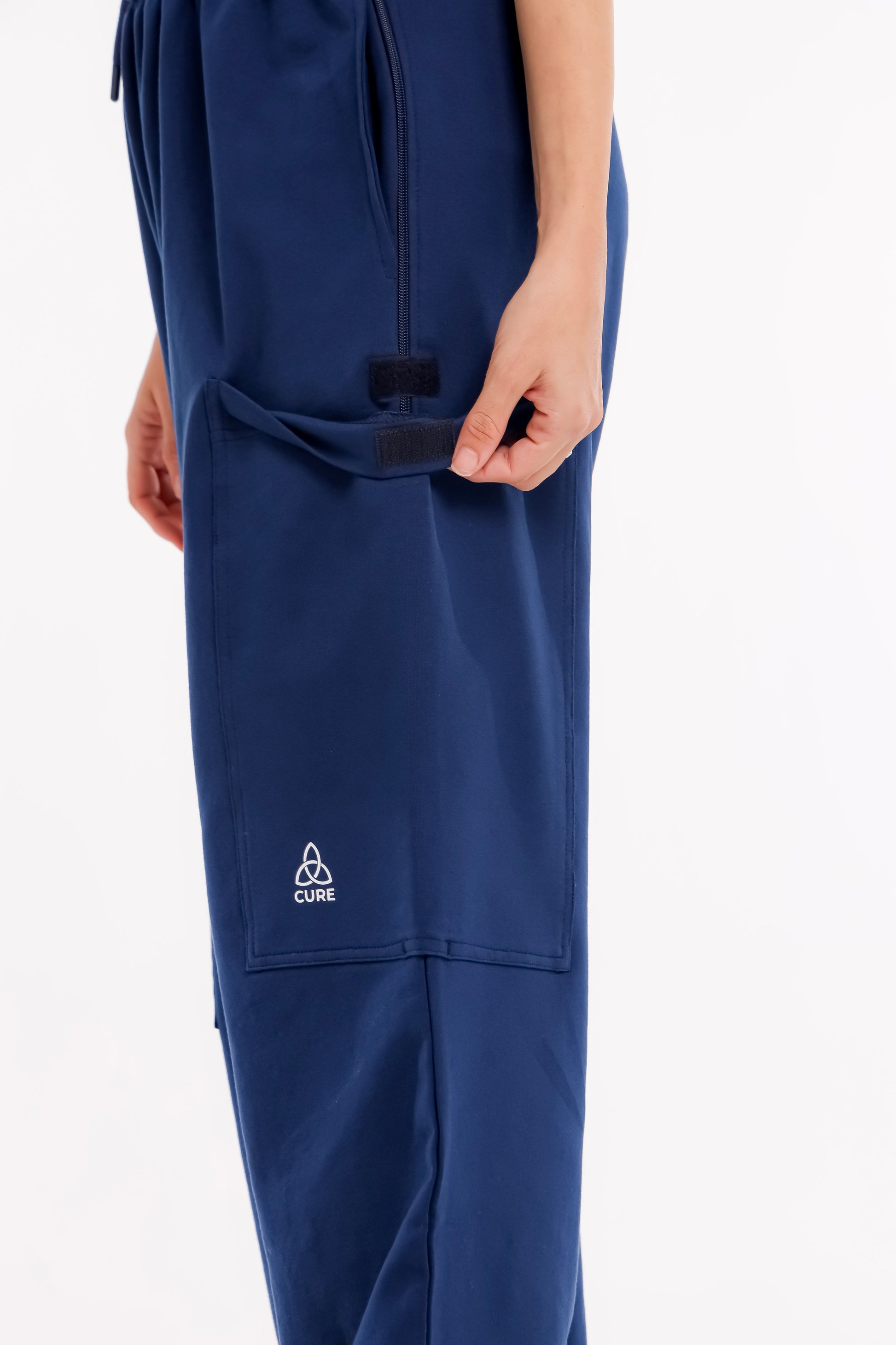 ComfortCure Adaptive Pflegehose für Prostatapatienten (mit Beintaschen), Navy, Detailansicht, Hand öffnet Klettklappe der Beintasche
