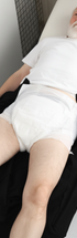 ComfortCure Adaptive Pflegehose für bettlägerige Patienten mit Klettverschluss, Schwarz, Aufsicht liegend, Hose heruntergezogen, Inkontinenzvorlage sichtbar